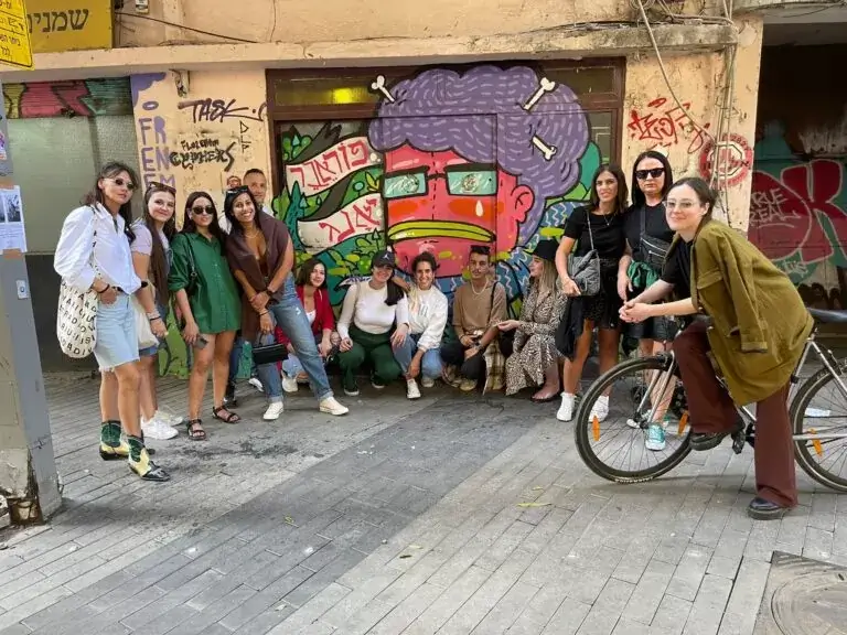 קבוצת אנשים מצטלמת מול גרפיטי צבעוני ברחוב